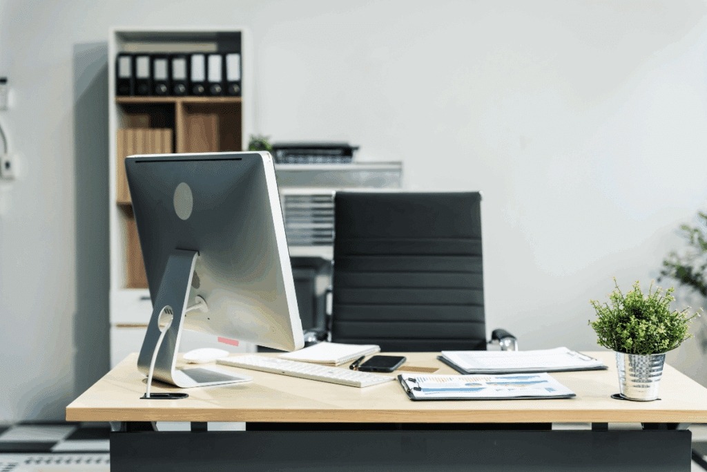 Bureau moderne avec un bureau en bois, un ordinateur de bureau et une chaise en cuir noir.