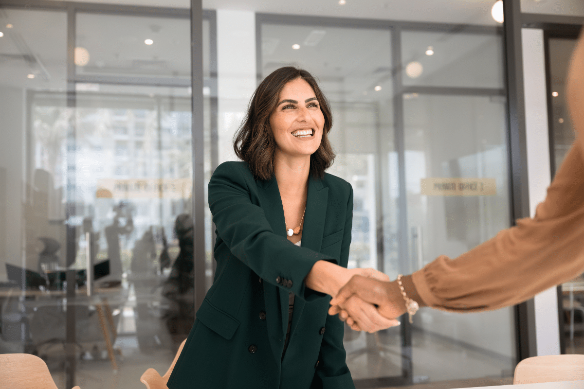 Accueillir un client dans ses bureaux Cheffe d'entreprise serrant la main d'un client tout en l'accueillant dans son bureau